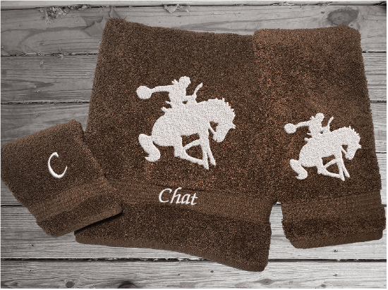 Brown High Quality Luxury Turkish Towels durable soft and absorbent, finished edges with a decorative band. Set has 1 bath towel, 1 hand towel, 1 washcloth. Embroidered with a custom design of a bronc rider. You can personalize the towel set with a name and an initial on the washcloth or just the designs. These luxury towels will make a wonderful hostess towel, wedding gift, housewarming gift, or for your own bathroom decor. Borgmanns Creations - 1
