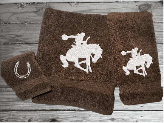 Brown High Quality Luxury Turkish Towels durable soft and absorbent, finished edges with a decorative band. Set has 1 bath towel, 1 hand towel, 1 washcloth. Embroidered with a custom design of a bronc rider. You can personalize the towel set with a name and an initial on the washcloth or just the designs. These luxury towels will make a wonderful hostess towel, wedding gift, housewarming gift, or for your own bathroom decor. Borgmanns Creations - 2