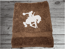 Load image into Gallery viewer, Brown  bath towel high quality luxury Turkish Towels durable soft and absorbent, finished edges with a decorative band. Set has 1 bath towel, 1 hand towel, 1 washcloth. Embroidered with a custom design of a bronc rider. You can personalize the towel set with a name and an initial on the washcloth or just the designs. These luxury towels will make a wonderful hostess towel, wedding gift, housewarming gift, or for your own bathroom decor. Borgmanns Creations - 3
