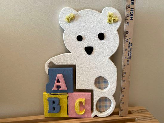 Wall hanging of a white teddy bear with color blocks cut from MDF board, panted with texture paint and top coat is white acrylic paint, eyes and nose are black pompoms, wire, flowers and material are added for finishing touches, hanger on back 12" x 15", makes a great design for you or a baby shower gift for a friend - Borgmanns Creations 
