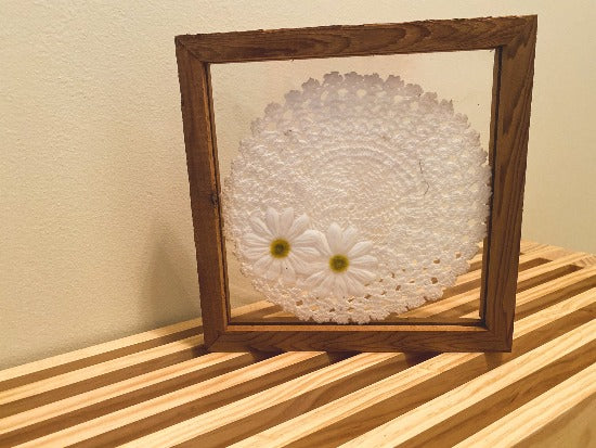 Crochet doily art one of a kind - white doily with 2 white flowers with green centers - wall hanging, or it can stand alone on any side - wonderful gift for the country farmhouse decor - bedroom decor ideas - doily is set between 2 pieces of acrylic and framed in wood. 10" H x 10" W x 1 1/4" D - Borgmanns Creations - 1