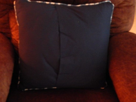 A picture of the back opening of the throw pillow cover of a western gun and holster set will make a unique home decor gift for the western theme home. 20" x 20" blue denim material, a diamond shape blue and white fabric to set off the embroidered design, quilted top, piping around edge, blue backing for opening in back. Embroidered and quilted custom wedding gift for the new couple's gift -Borgmanns Creations