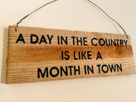 Wood sign wall hanging is cedar upcycled fence panel with the saying "A day in the country is like a month in town" ,hand painted, hung by wire, 11" x 4", would be a unique one of a kind house warming gift, birthday, wedding shower, wedding gift etc. The natural wood color will go with any room -Borgmanns Creations 