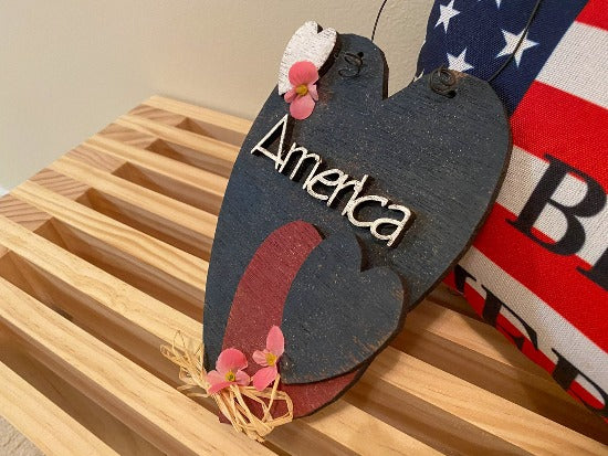 Holiday decor "America" wall art will add to your home decor - laser cut Luan wood painted with acrylic paint glued together, flowers and raffia to complete the wall art - home decor for kitchen, living room, den or hallway - perfect summer and 4th of July decoration, Valentines Day, Memorial Day, Labor Day, etc.  - Borgmanns Creations - 2