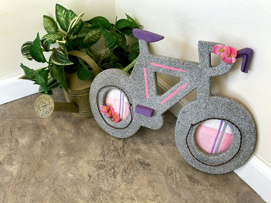 Wood wall hanging this wood sculpture of a bike will make a wonderful baby shower gift for girls room.  1/2" MDF board, layered wood, hand painted with gray acrylic paint, pink stripes, purple seat, handle bars an peddle,  decorated with flowers, wire, and material, hanging hook on the back. The perfect gift you may be looking for - Borgmanns Creations 