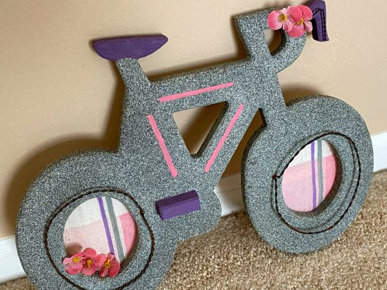 Wood wall hanging this wood sculpture of a bike will make a wonderful baby shower gift for girls room. 1/2" MDF board, layered wood, hand painted with gray acrylic paint, pink stripes, purple seat, handle bars an peddle, decorated with flowers, wire, and material, hanging hook on the back. The perfect gift you may be looking for - Borgmanns Creations